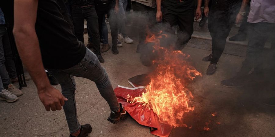 Deonstrierende treten vor dem Konsulat auf eine brennende türkische Flagge.