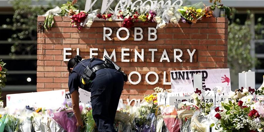 Ein Polizeibeamter legt Blumen vor der Robb Elementary School in der Stadt Uvalde, Texas, USA, nieder. Foto: Wu Xiaoling/XinHua/dpa