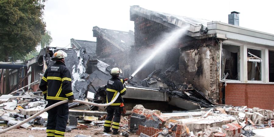Feuerwehrleute löschen Trümmer eines Gebäudes der Stadtteilschule Finkenwerder.