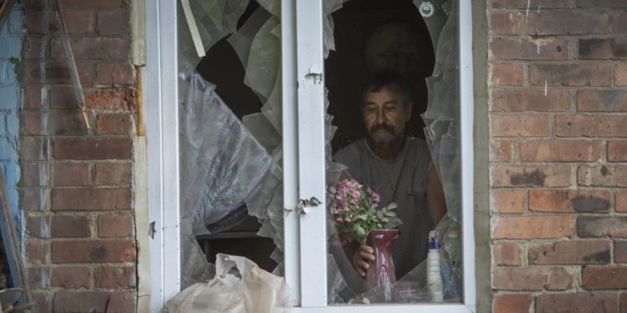 Ein Mann in Bachmut stellt in seinem durch russischen Beschuss beschädigten Haus Blumen  auf die Fensterbank. Foto: Efrem Lukatsky/AP/dpa