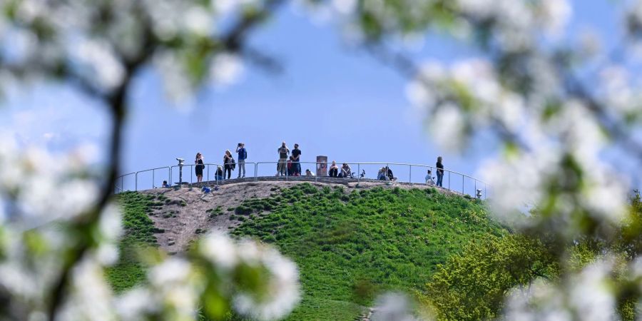 Ausflügler auf dem Olympiaberg in München erfreuen sich der Sonne.