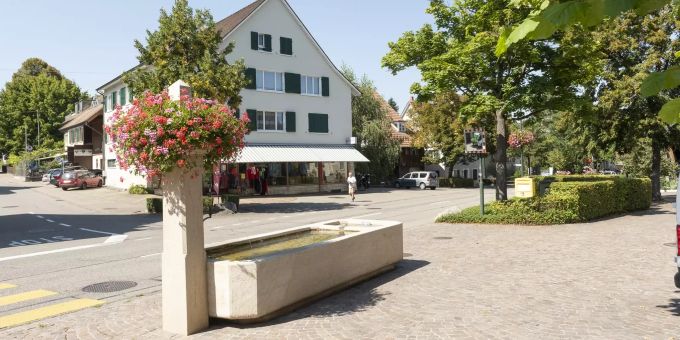 Brunnen an der Hauptstrasse in Ettingen. Ettingen hat mit der Tramline 10/17 (ehem. Birsigtal-Bahn) eine direkte Verbindung nach Basel. Brunnen an der Hauptstrasse in Ettingen. Ettingen hat mit der Tramline 10/17 (ehem. Birsigtal-Bahn) eine direkte Verbindung nach Basel.