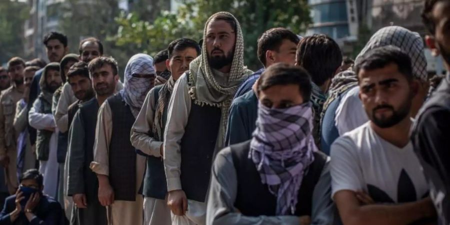 Afghanische Männer warten vor einer Bank in Kabul, um Geld abzuheben. Foto: Oliver Weiken/dpa