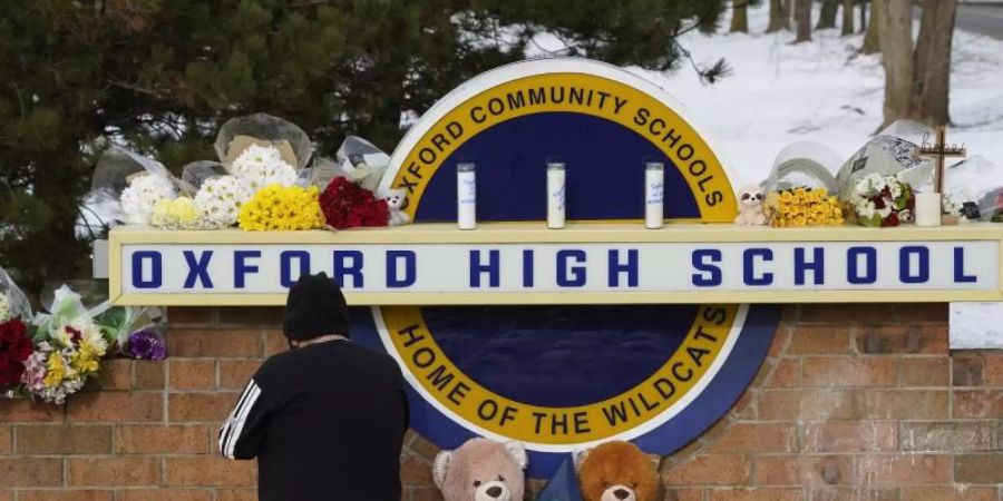 Eine Frau kniet zum Gebet vor dem Schild der Oxford High School im US-Bundesstaat Michigan. Ein 15-Jähriger hat dort mindestens vier seiner Mitschüler getötet. Foto: Paul Sancya/AP/dpa