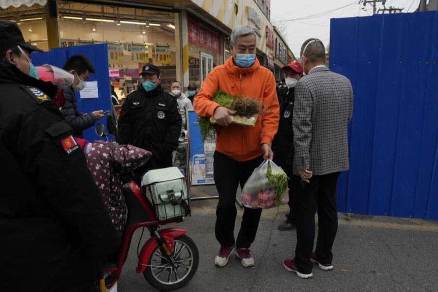 Ein Mann verlässt einen Nahrungsmittelladen in Peking am 24. November 2022. Die blauen Barrikaden wurden als Folge eines lokalen Lockdowns installiert.