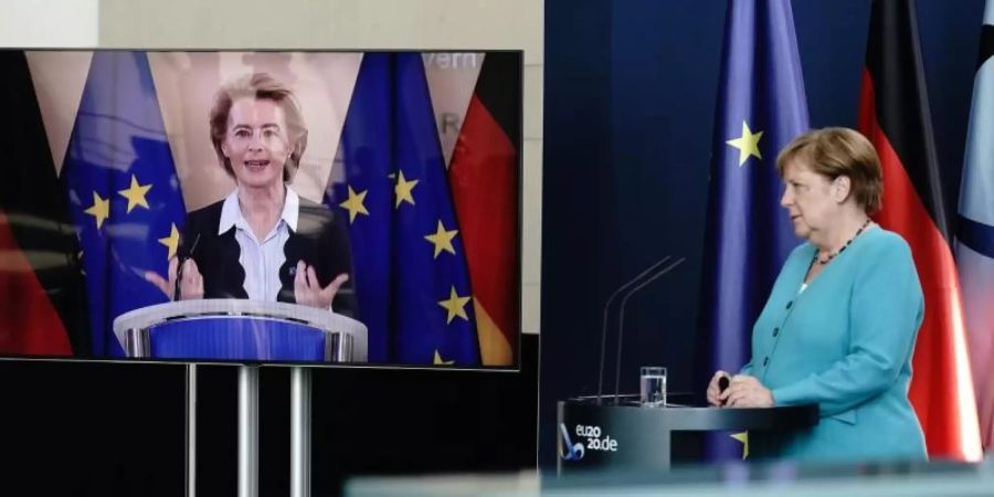 Bundeskanzlerin Angela Merkel (CDU) hört im Foyer des Bundeskanzleramtes EU-Kommissionspräsidentin Ursula von der Leyen (CDU), die per Video zugeschaltet ist, zu. Foto: Kay Nietfeld/dpa