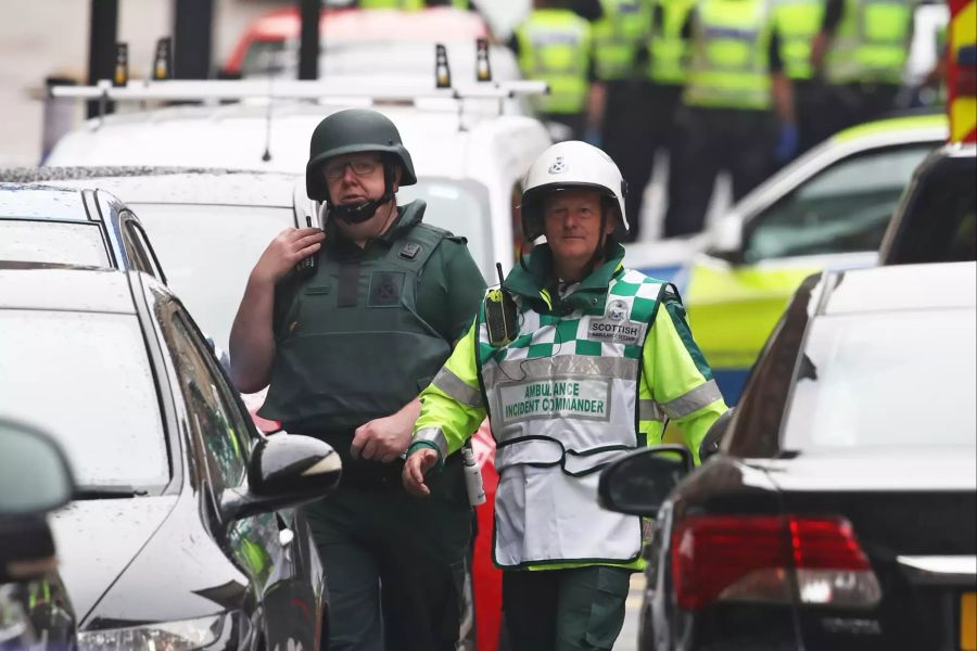 Mitarbeiter des Rettungsdienstes stehen am abgesperrten Tatort in Glasgow.