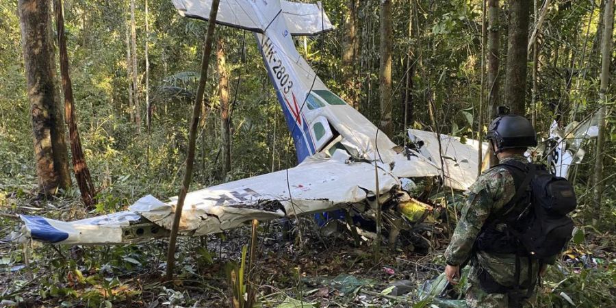 HANDOUT - Auf diesem von der Pressestelle der kolumbianischen Streitkräfte veröffentlichten Bild steht ein Soldat vor dem Wrack einer Cessna C206, die im Dschungel von Solano im kolumbianischen Bundesstaat Caqueta abgestürzt ist. Foto: -/Colombia's Armed Forces Press Office/dpa - ACHTUNG: Nur zur redaktionellen Verwendung und nur mit vollständiger Nennung des vorstehenden Credits