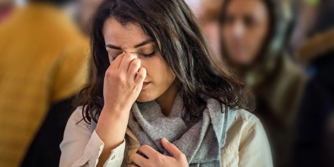 Menschenmengen und andere Alltagssituationen stellen für Hochsensible eine Herausforderung dar. Frau hält sich Kopf