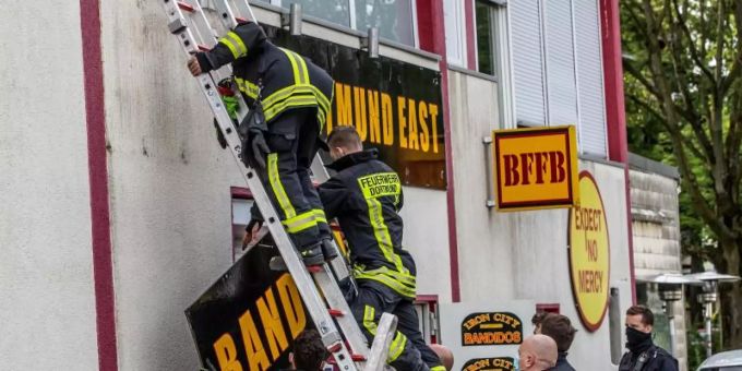 Feuerwehrleute entfernen unter Polizeischutz ein Schild am Vereinsheim der Rockergruppe «Bandidos». Foto: Dieter Menne/dpa Feuerwehrleute entfernen unter Polizeischutz ein Schild am Vereinsheim der Rockergruppe «Bandidos». Foto: Dieter Menne/dpa