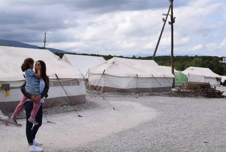 In einem Camp in Serbien halt Crnojevic ein Kind auf dem Arm.