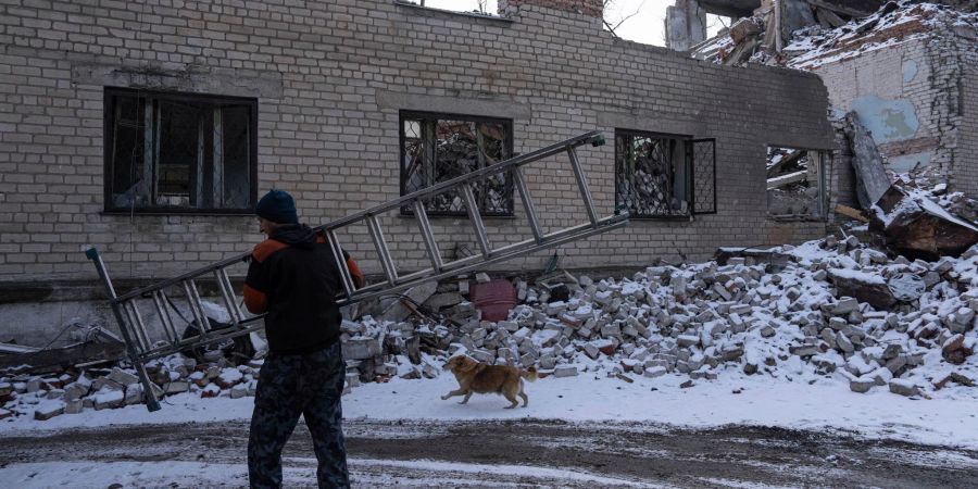 Ein Mann trägt eine Leiter durch ein zerstörtes Gebiet im ukrainischen Awdijiwka.