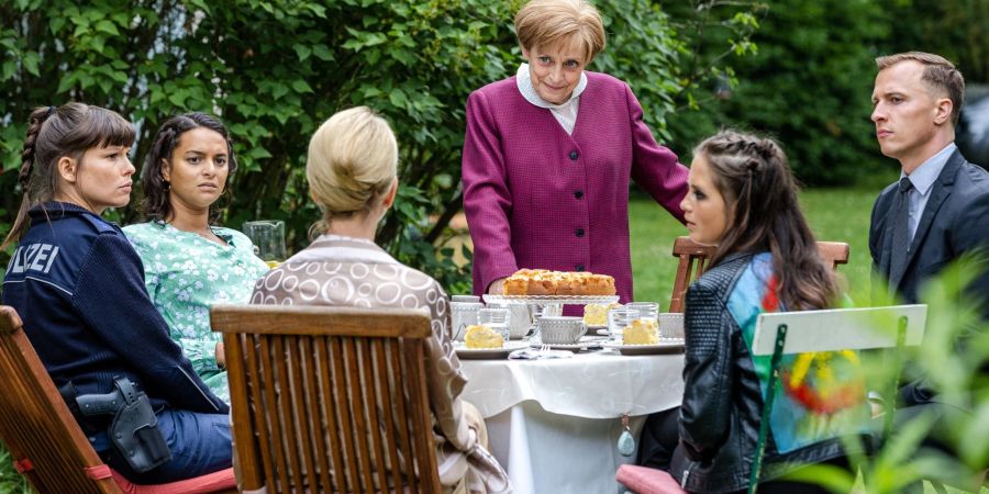 Miss Merkel (Katharina Thalbach, 4.v.l.) löst den Mordfall.