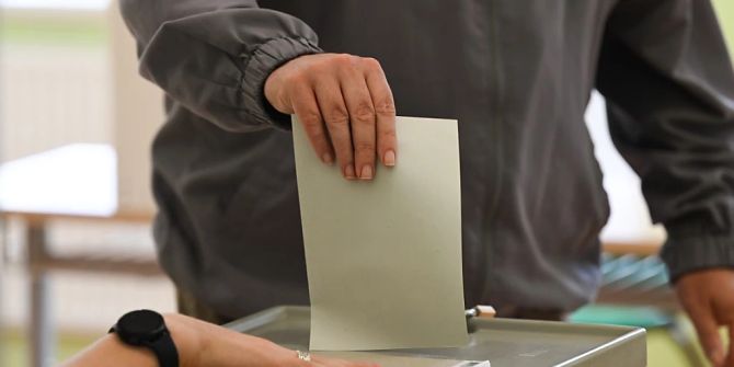Ein Mann wirft seinen Stimmzettel in eine Wahlurne.