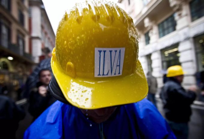 Ein Mann trägt einen Bauhelm mit dem Logo von ILVA. Ilva