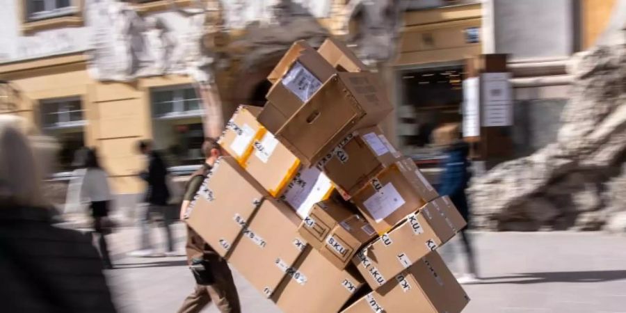 Ein Paketzulieferer transportiert mit einer Sackkarre mehrere Pakete durch die Fussgängerzone. Foto: Peter Kneffel/dpa