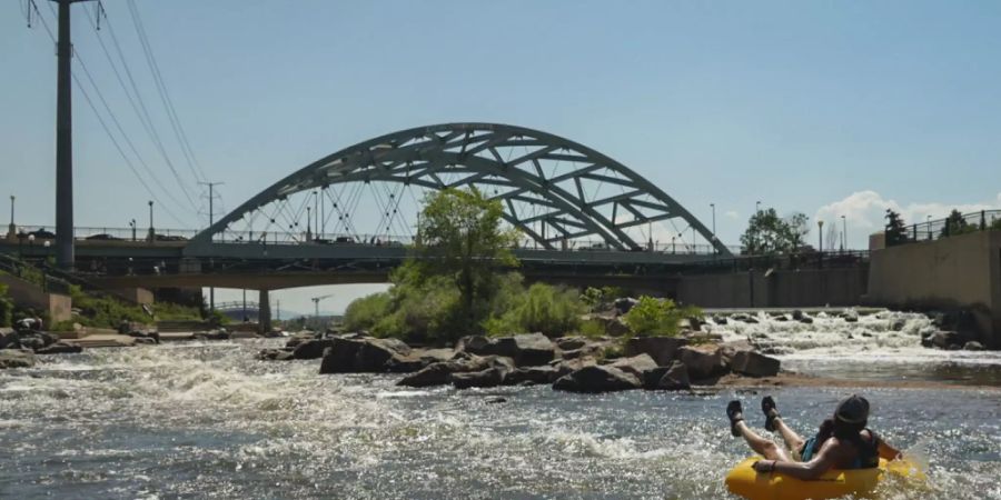 Menschen kühlen sich im Wasser ab, am Zusammenfluss von South Platte River und Cherry Creek. Am Nachmittag erreichte die Temperatur 35 Grad Celsius als Teil der Hitzewelle, die über den Westen der USA hinwegfegt. Foto: Brittany Peterson/AP/dpa