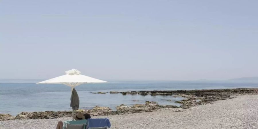 Touristen geniessen den Ritsa-Strand in Kardamyli, einer Stadt am Meer fünfunddreissig Kilometer südöstlich von Kalamata, Peloponnes. Foto: Socrates Baltagiannis/dpa