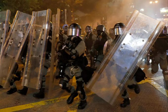 Bereitschaftspolizei in Schutzausrüstung schützt sich bei einer Konfrontation mit Demonstranten mit Schildern. Demonstrationen in Hongkong