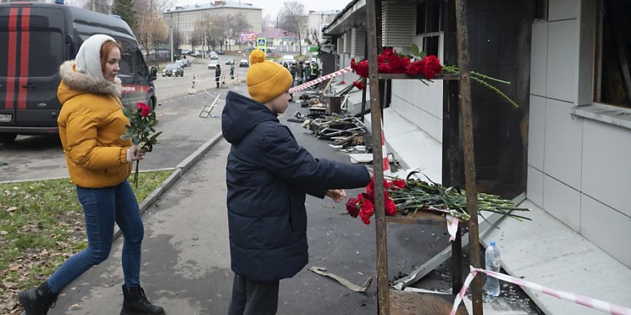 Ein Junge (r) legt eine rote Nelke nieder, nach einem Brand in einem Nachtclub. Nach dem Brand in einem russischen Nachtclub mit mehreren Toten ermitteln die Behörden wegen Fahrlässigkeit mit Todesfolge. Foto: Dmitry Serebryakov/AP/dpa