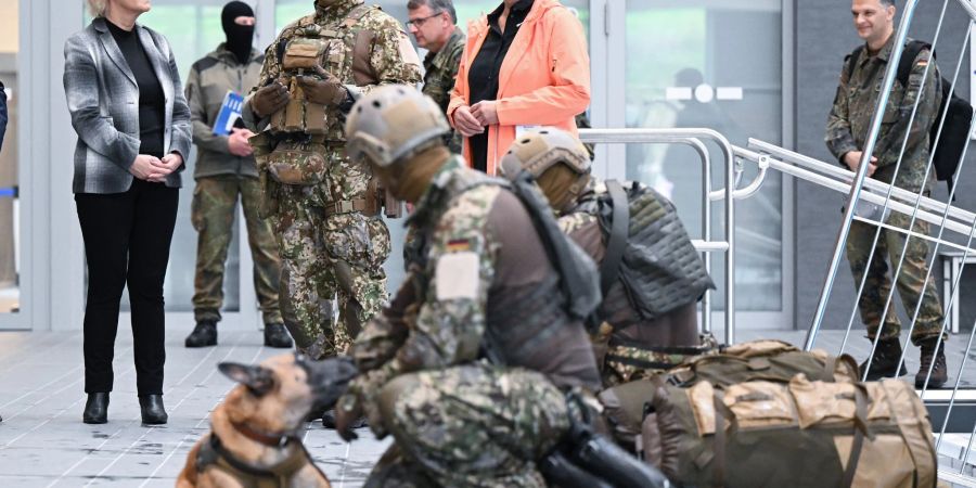 Bundesverteidigungsministerin Christine Lambrecht (l, SPD) sieht sich bei ihrem Besuch beim Kommando Spezialkräfte (KSK) in einer Schwimmhalle eine Ausbildungsübung mit einem Hund an.