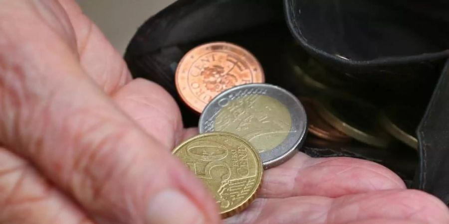 Eine Rentnerin hält einen Geldbeutel mit verschiedenen Euromünzen. Foto: Karl-Josef Hildenbrand/dpa