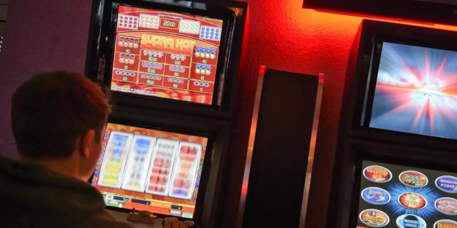 Ein junger Mann spielt an einem Spielautomaten. Foto: Britta Pedersen/zb/dpa