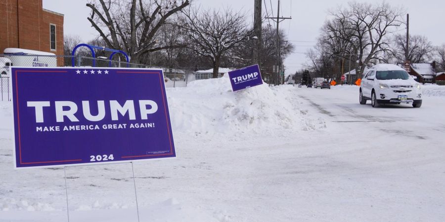 Ein Wahlplakat des ehemaligen US-Präsidenten Trump steht im Schnee. Bei der ersten Vorwahl der Republikaner um die US-Präsidentschaftskandidatur der Partei hat Trump einen Sieg eingefahren.