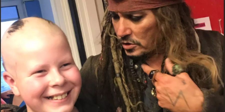 Johnny Depp macht ein Foto mit einem krebskranken Kind.
