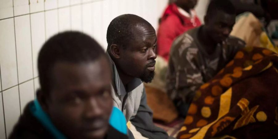 Migranten von Ghana, Nigeria und dem Tschad sitzen auf dem Boden eines Flüchtlingslagers im Zoo von Tripolis.