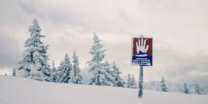 Ein Gefahrenschild warnt vor Lawinen im Schnee.