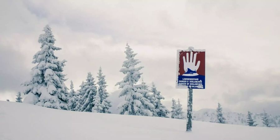Ein Gefahrenschild warnt vor Lawinen im Schnee.
