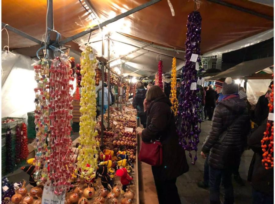 Passanten begutachten die Zwiebeln an einem Stand.