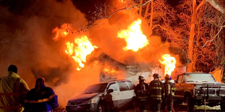 Feuerwehrleute löchen ein brennendes Haus.