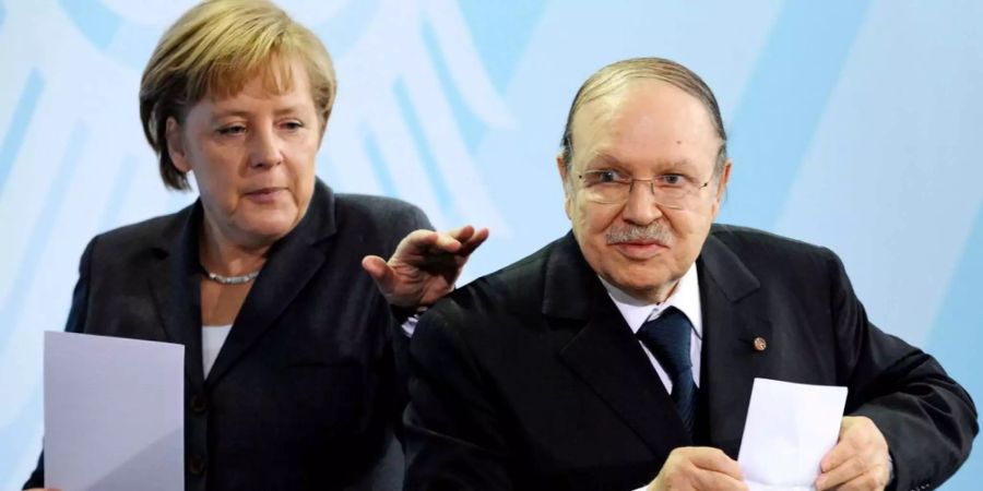 Die deutsche Bundeskanzlerin Angela Merkel (CDU) und der Präsident der Demokratischen Volksrepublik Algerien, Abdelaziz Bouteflika, halten im Bundeskanzleramt in Berlin während der Begegnung mit der Presse Zettel in den Händen.