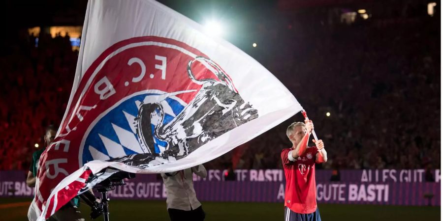 Bastian Schweinsteiger von München steht nach dem Spiel mit einer FC Bayern-Fahne auf dem Platz.