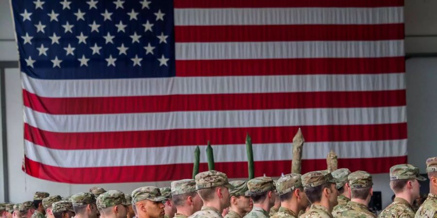 US-Soldaten sind während einer militärischen Zeremonie in den Storck-Barracks in Illesheim (Bayern) vor einer Flagge der Vereinigten Staaten von Amerika zu sehen.