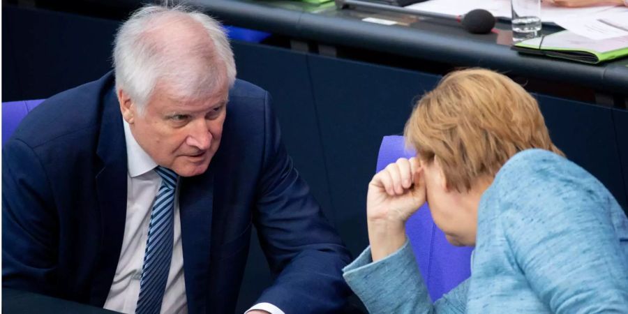 Horst Seehofer, Bundesminister des Innern, für Bau und Heimat, und Bundeskanzlerin Angela Merkel nehmen an der Plenarsitzung im Deutschen Bundestag teil.