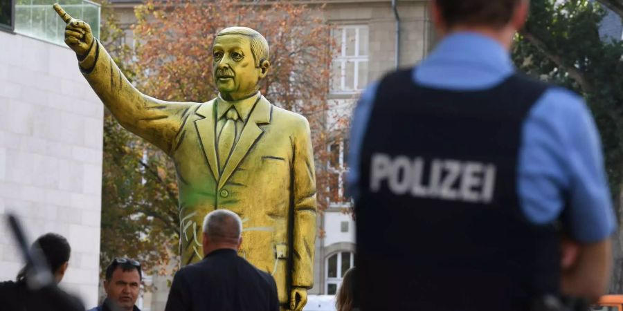 Passanten und Polizei stehen auf dem Platz der Deutschen Einheit vor einer goldenen Erdogan-Statue.