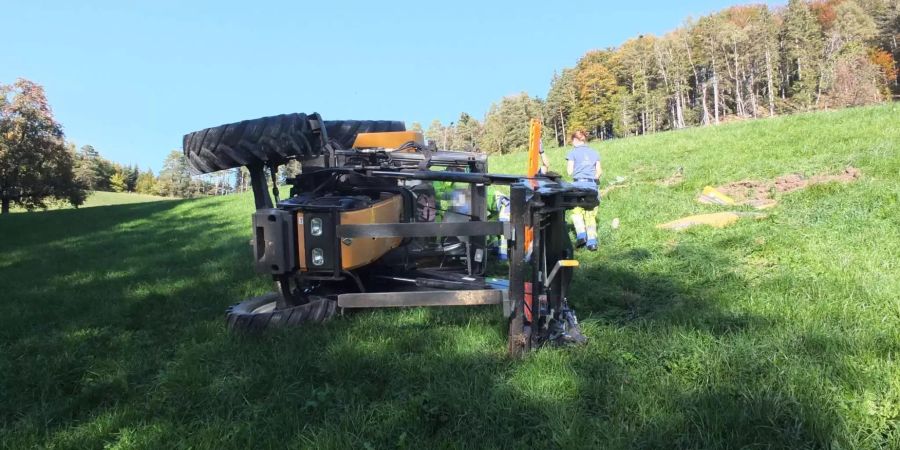 Der auf der Seite liegende Traktor in einer Wiese in Kirchberg SG wird von Ermittlern der Kantonspolizei St. Gallen untersucht.