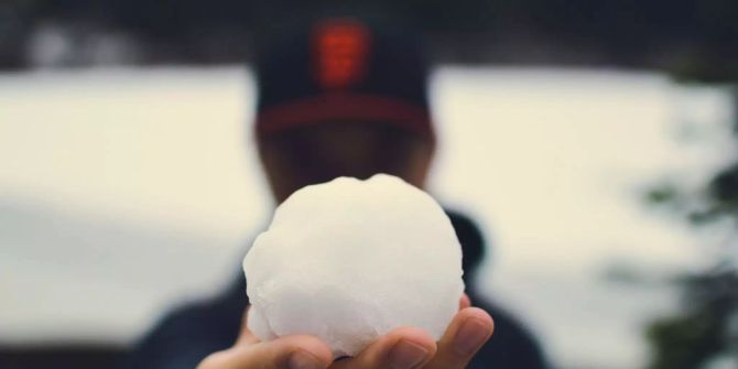 Ein Mann hält ein Schneeball in der Hand.