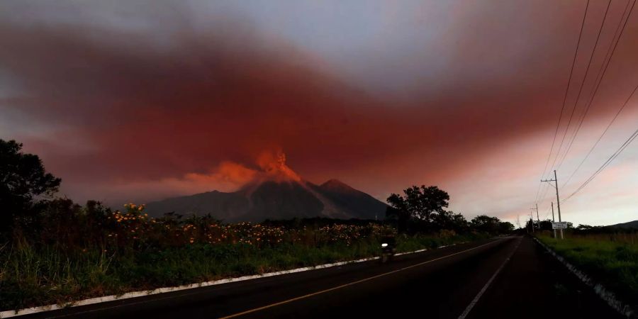 Guatemala, El Rodeo: Eine Wolke aus roter Asche hängt über einer Autobahn in der Nähe des Volcan de Fuego (Feuervulkan). Der Volcán de Fuego (Feuervulkan) in Guatemala ist erneut ausgebrochen und hat viele Menschen in die Flucht getrieben.