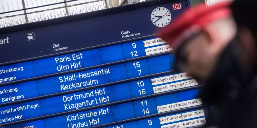 Ein Kondukteur stehen am Stuttgarter (D) Hauptbahnhof vor einer Informationstafel der Deutschen Bahn.