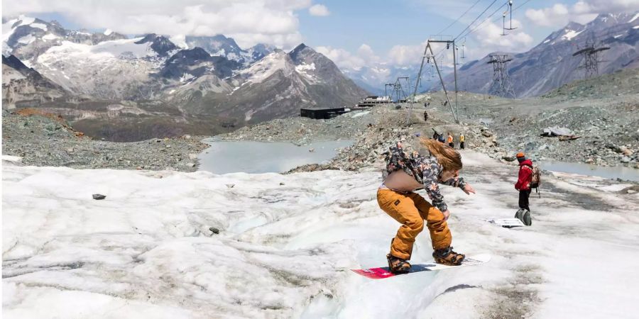 Der Snowboarder Samuel Camenzind springt über einen Fluss aus schmelzendem Gletschereis auf der Oberfläche des Theodulgletschers oberhalb der Station Trockener Steg in Zermatt VS.