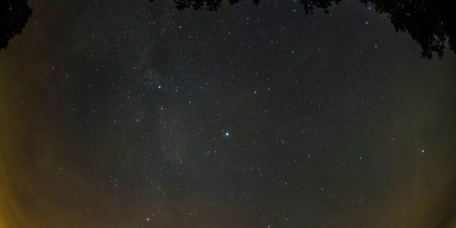 Eine Sternschnuppe leuchtet neben der Milchstrasse am Himmel über dem Walchensee (D).