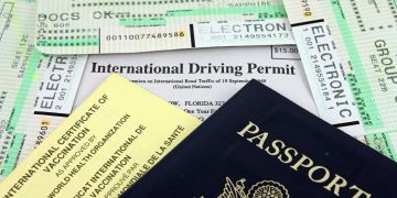 Passport und international Driving Permit mit Papieren auf einem Tisch.
