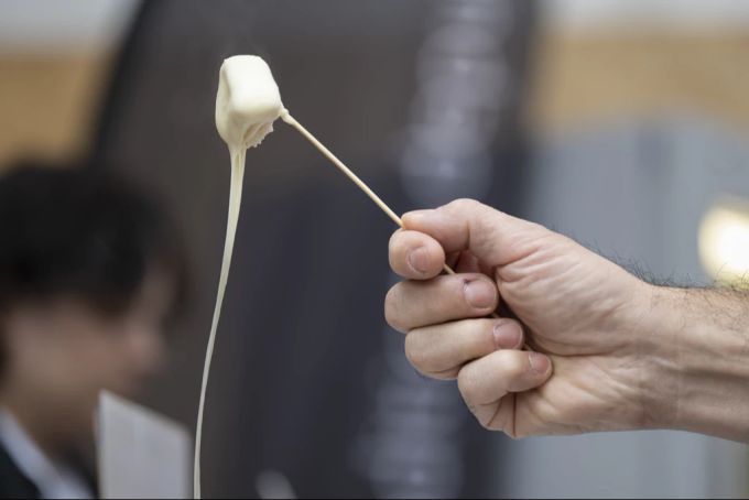 Ein Besucher probiert ein Fondue während des 1. Schweizer Fondue-Festivals am 17. November 2022, auf dem Place Georges-Python in Freiburg. Diese erste Ausgabe stellte das Moitié-Moitié-Fondue in den Mittelpunkt. Fondue Moitié-Moitié