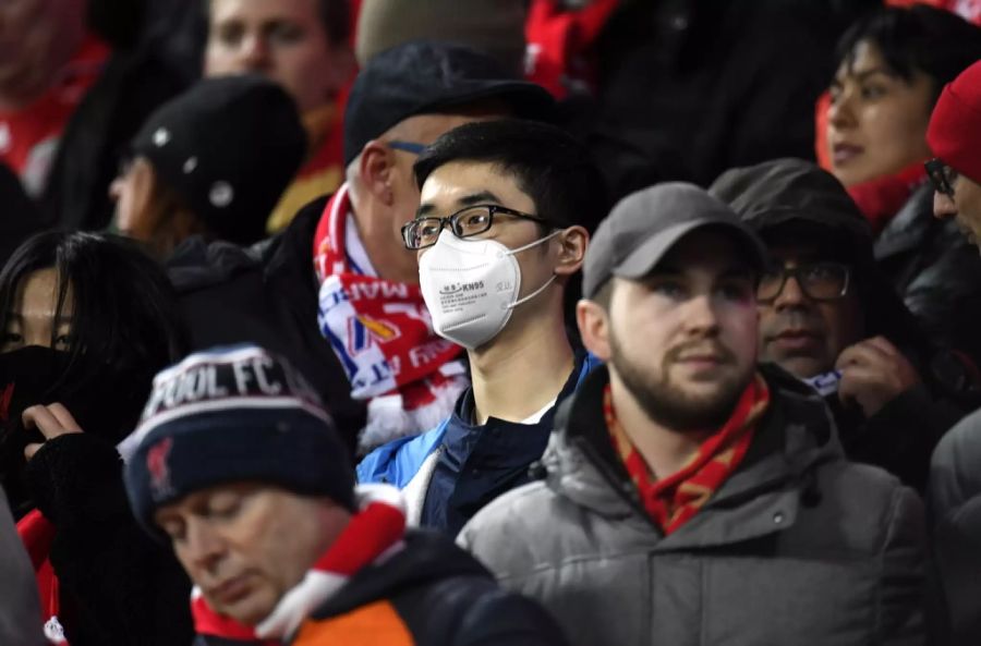 Ein Fan auf der Tribüne versucht sich mit einer Maske zu schützen.