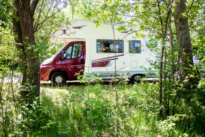 Ein Wohnmobil steht hinter Bäumen auf einem Parkplatz. (Symbolbild) Camping an der Nordseeküste