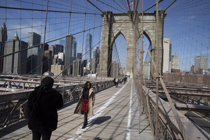 Eine Touristin posiert für ein Erinnerungsfoto auf der Brooklyn Bridge in New York. new york tourismus